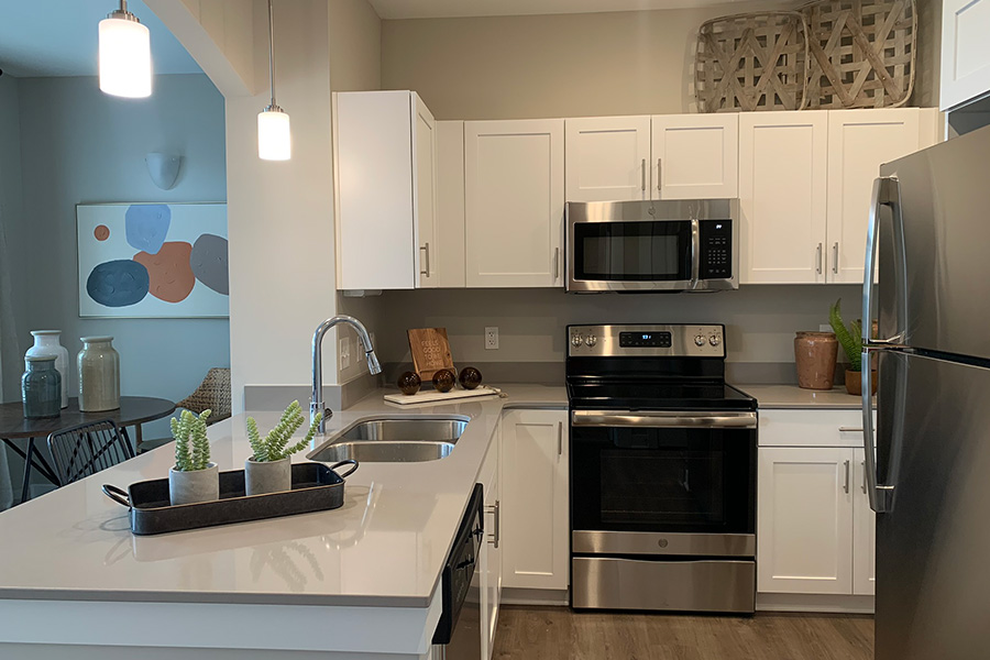 Kitchen at Harmony Apartments with white cabinets and stainless steel appliances.