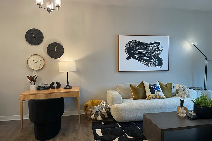 A simple color palette, different textures, and items grouped in threes give this Continuum Apartments living room a stylish look. Black and white decor in an apartment living room