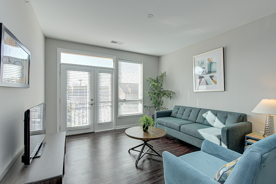 Living room at Riverview Apartments with sofa, chair, and TV stand.